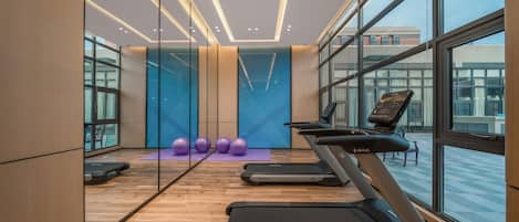 A modern gym with treadmills, exercise balls, and a large window.