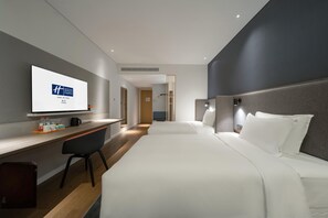A modern hotel room with a bed, a desk, and a television displaying the hotel’s logo. - Holiday Inn Express Yixing (Wuxi)