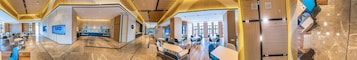 Un lobby moderno de hotel con un mostrador de recepción central, áreas de descanso y vistas al comedor.