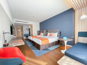 A modern hotel room with a large bed, a desk, a chair, and a small table. - Holiday Inn Express Yixing (Wuxi)