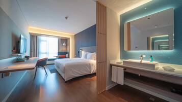 A modern hotel room with a bed, bedside table, and a large mirror.