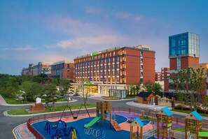 A hotel with a playground, a road, and a building with a green sign. - Holiday Inn Express Yixing (Wuxi)