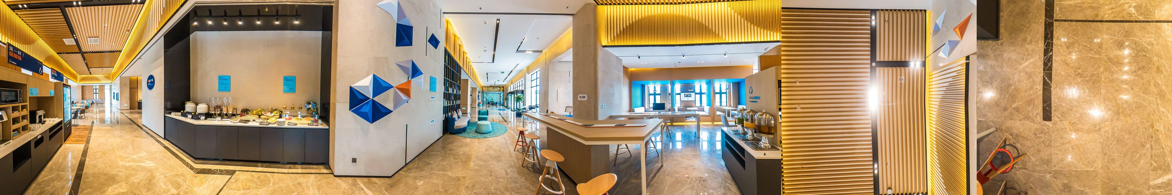 A modern hotel lobby with a reception desk, seating area, and a view of the lobby in the background.