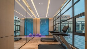 Academia moderna com esteiras, bolas de exercício e uma grande janela.