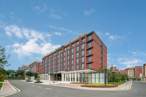 A modern hotel with a brick facade, large windows, and a landscaped entrance. - Holiday Inn Express Yixing (Wuxi)