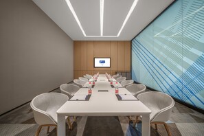 A conference room with a long table, chairs, water bottles, and a screen on the wall. - Holiday Inn Express Yixing (Wuxi)