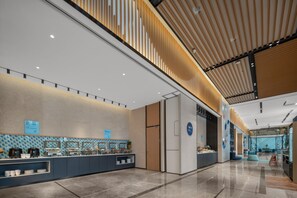A modern hotel lobby with a long reception desk, a large refrigerator, and a high ceiling with wooden slats. - Holiday Inn Express Yixing (Wuxi)