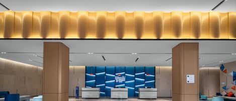 A modern reception area with a central desk, seating, and a decorative wall.