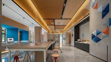 Un interior moderno con un mostrador de recepción alargado, taburetes de bar y una barra con productos alimenticios.