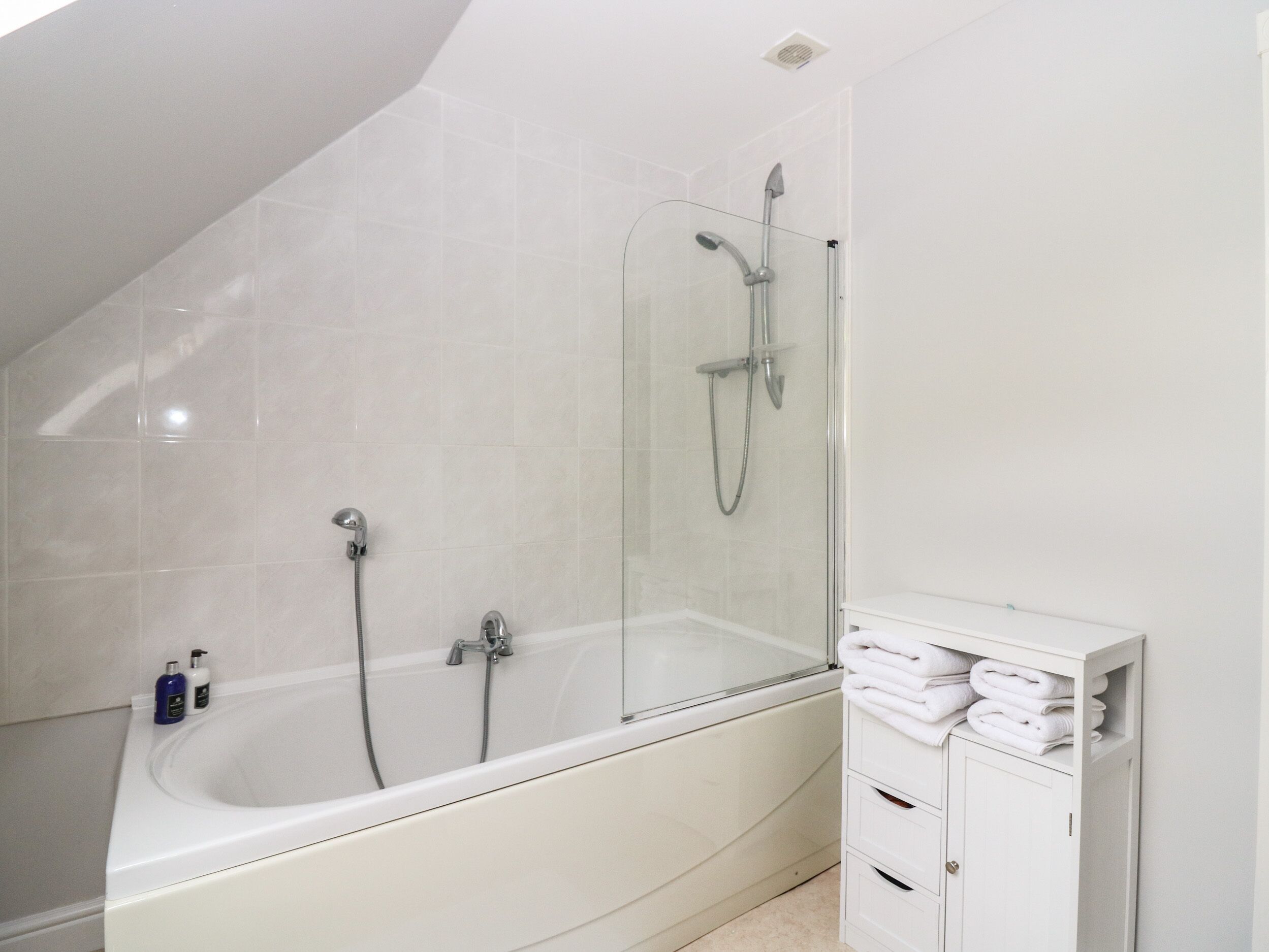 Un baño moderno con una bañera independiente, ducha con cerramiento de vidrio y tocador blanco con toallas.