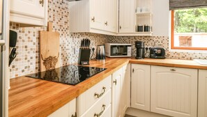 A kitchen with white cabinets, a wooden countertop, a microwave, a coffee maker, and a toaster. - Tombeck (Ballindalloch)