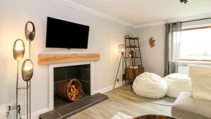 A modern living room with a fireplace, a mounted TV, and a large bean bag chair. - Tombeck (Ballindalloch)