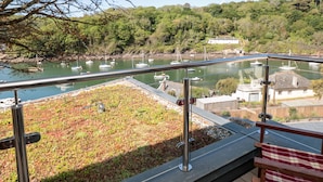 A balcony with a view of a harbor, a grassy area, and a wooden fence. - 3 The Hide (Plymouth)