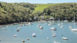 A marina with numerous boats docked, surrounded by lush green hills and a clear sky. - 3 The Hide (Plymouth)