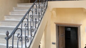 A staircase with ornate black railings leading to a landing with a wooden door and a small table.