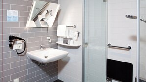 A modern bathroom with a glass shower enclosure, a white sink with a mirror above it, and a towel rack.