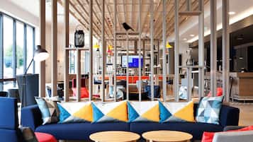 A modern interior with a blue sofa, wooden tables, and a variety of colorful pillows.