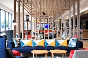 A modern interior with a blue sofa, wooden tables, and a variety of colorful pillows.