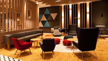A modern lounge area with a sofa, chairs, and a geometric wall design.