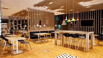 A modern restaurant with wooden flooring, multiple seating areas including booths and tables, and pendant lighting.