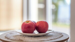 Un plato con dos manzanas sobre una mesa con un mantel de encaje.