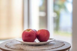 A plate with two apples on a table with a lace doily.