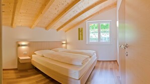 Un dormitorio con techo de madera, una cama, una mesita de noche, una ventana y una puerta.