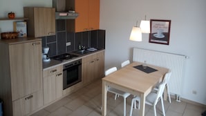 Een moderne keuken met houten kastjes, een fornuis en een eettafel met stoelen.