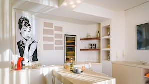 A modern kitchen with a dining area, featuring a large abstract painting, a wine rack, and a minimalist design. - Villa Politia   Luxury Villa with a Spectacular City View (Athens)