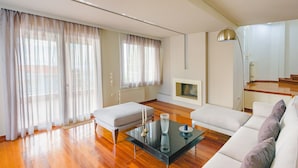 A modern living room with a sofa, a glass coffee table, and a fireplace. - Villa Politia   Luxury Villa with a Spectacular City View (Athens)
