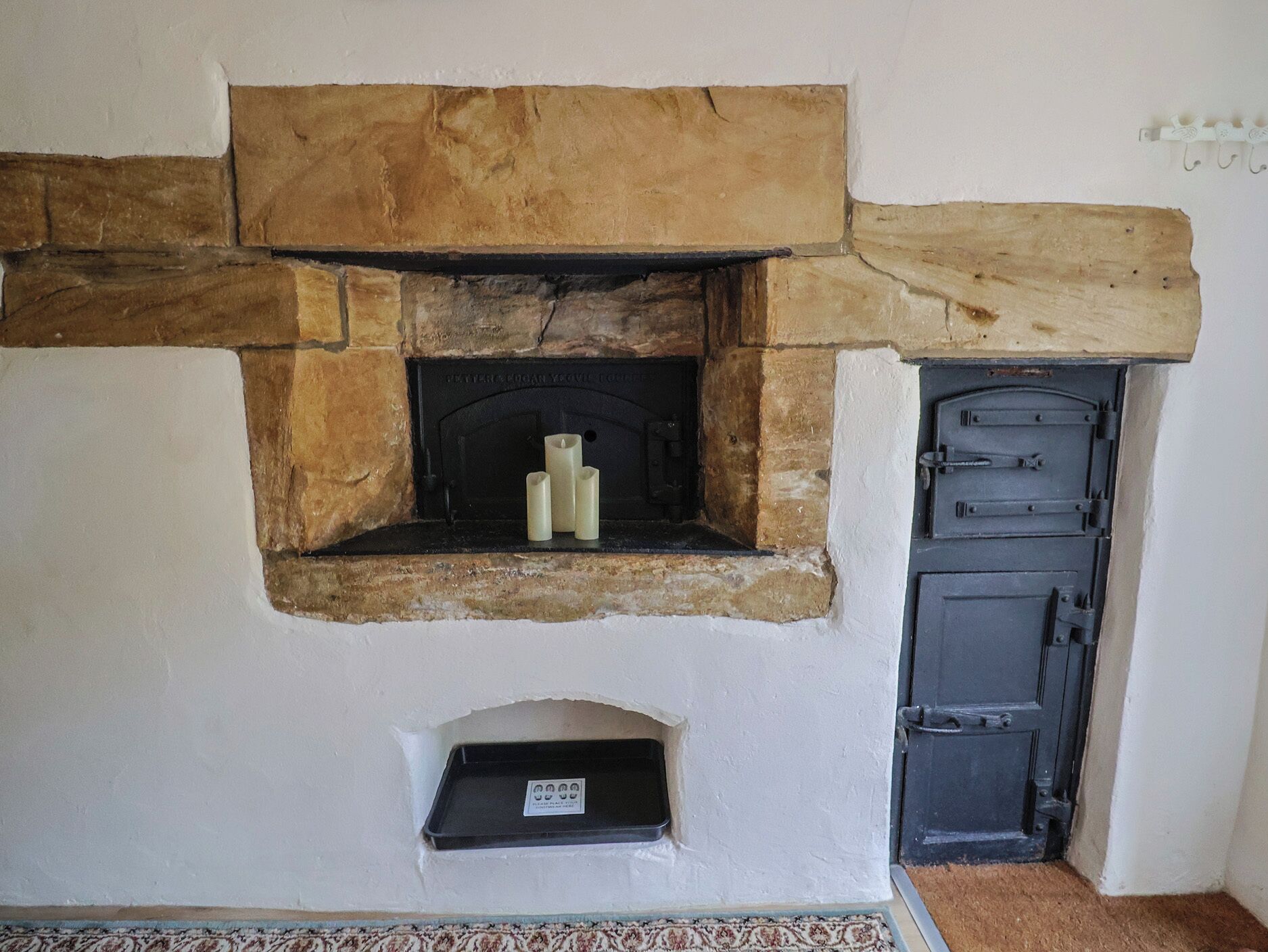 A stone fireplace with a black door to the right.