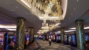 A spacious casino interior with multiple slot machines, a central walkway, and decorative hanging lights.