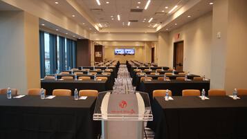 A conference room with rows of tables, chairs, and a podium.