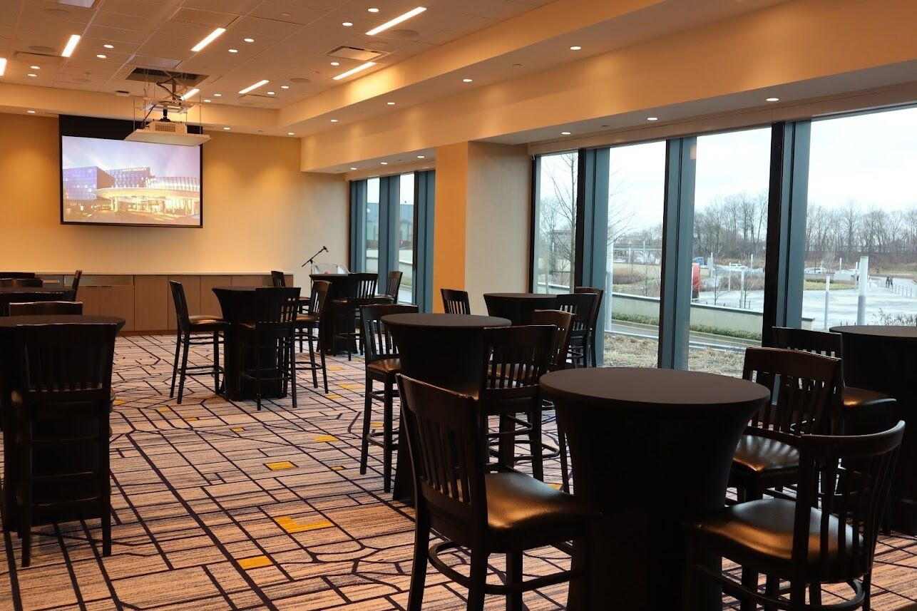 A conference room with a large screen, chairs, tables, and a patterned carpet.