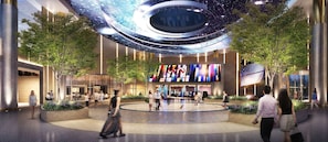 Un bâtiment moderne doté d’un atrium central, de grands écrans numériques et d’une verrière circulaire.