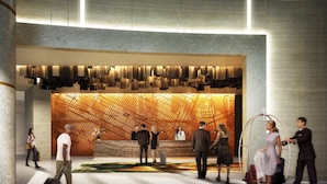 A modern hotel lobby with a geometric patterned wall, a reception desk, and a luggage carousel.