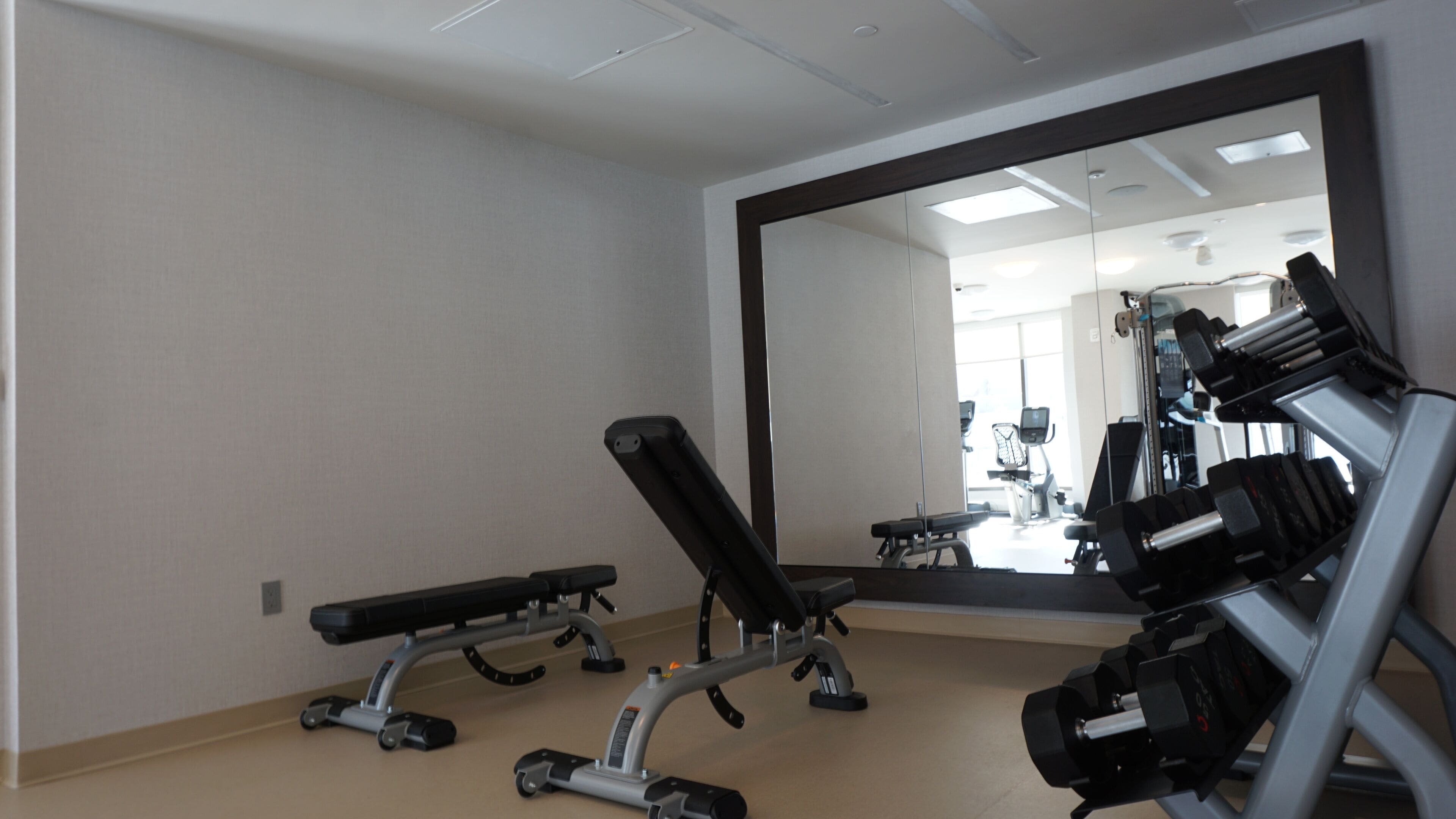 A gym with weightlifting equipment and a large mirror.