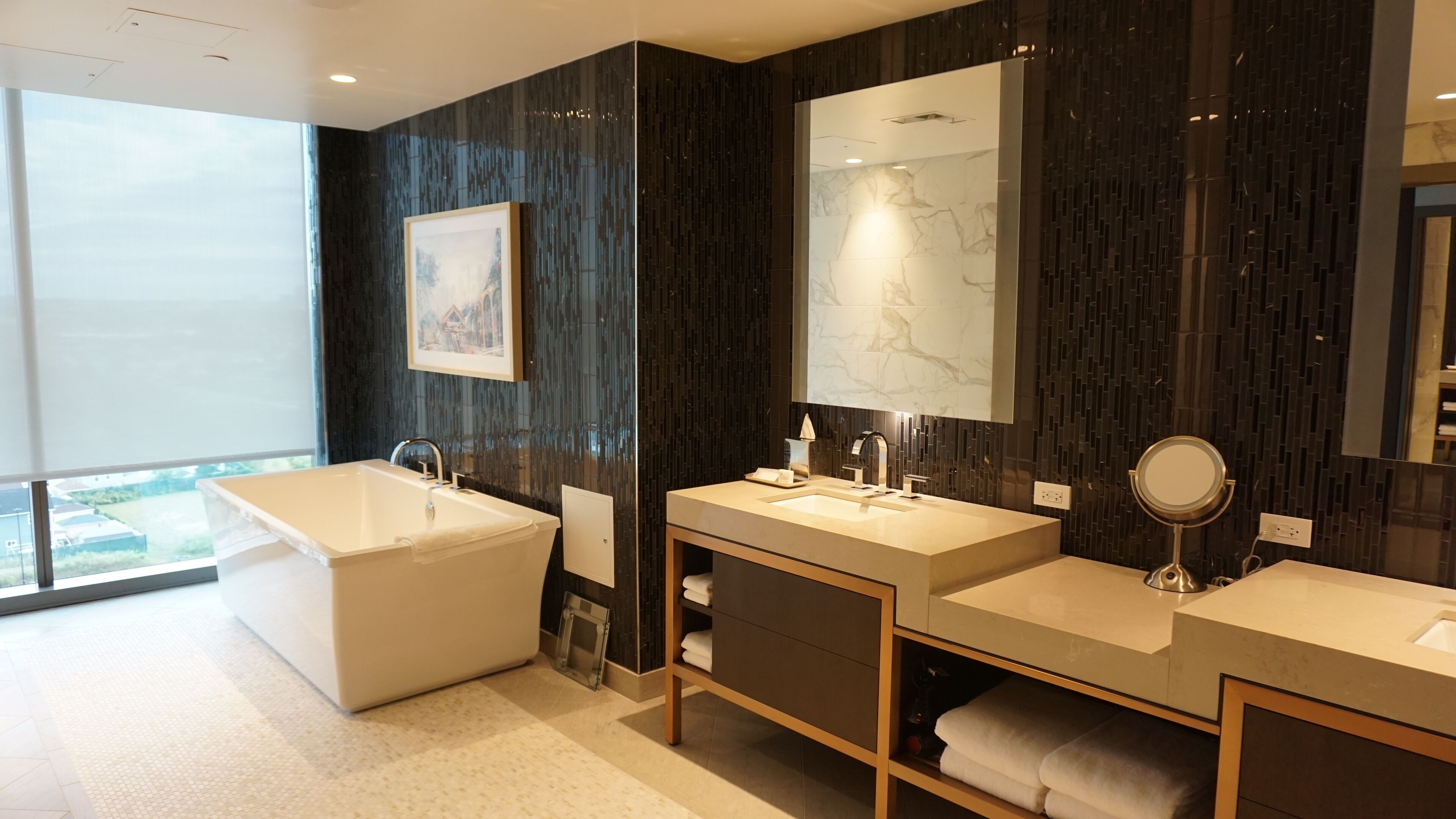 Une salle de bain moderne avec une grande baignoire, deux lavabos, un miroir et un tableau encadré au mur.