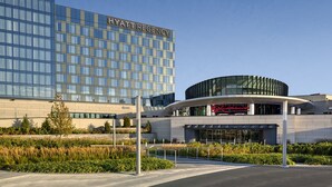 A modern Hyatt Regency hotel with a large glass facade and a distinctive curved entrance.