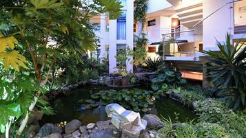 A modern building with a rooftop garden, a pond with lily pads, and a metal sculpture.