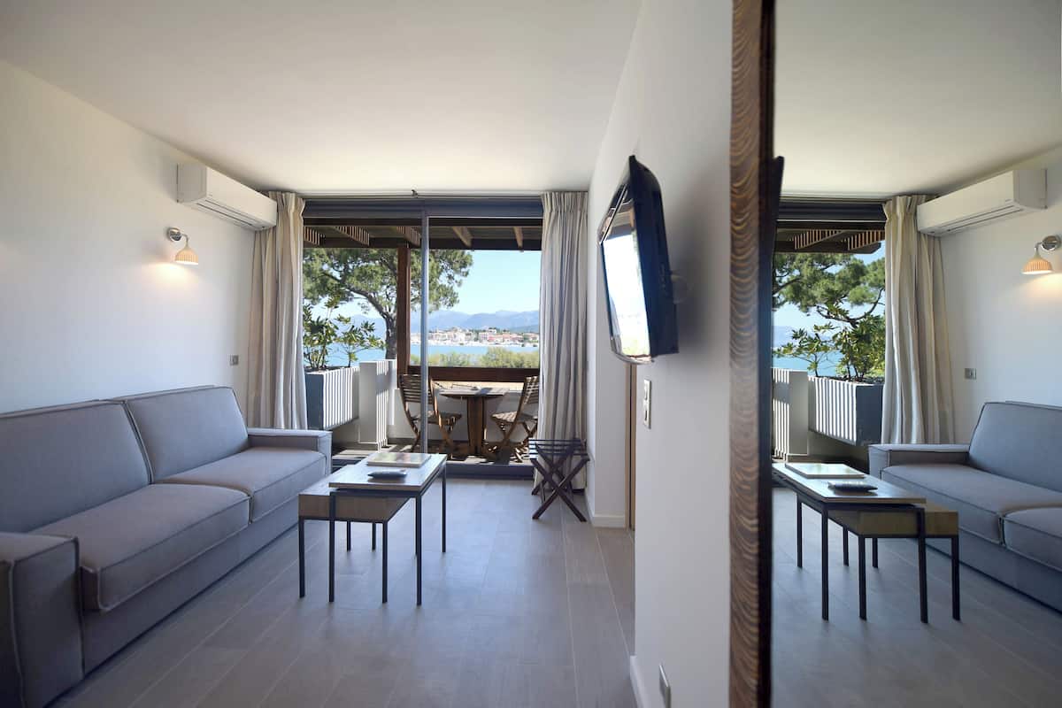 A modern living room with a sofa, two tables, and a TV on the wall.
