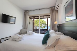 Hotellihuone, jossa on sänky, televisio, ikkuna verhoilla ja näkymä ulos.