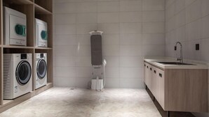 Uma casa de banho moderna com máquina de lavar embutida, porta-toalhas e lavatório.