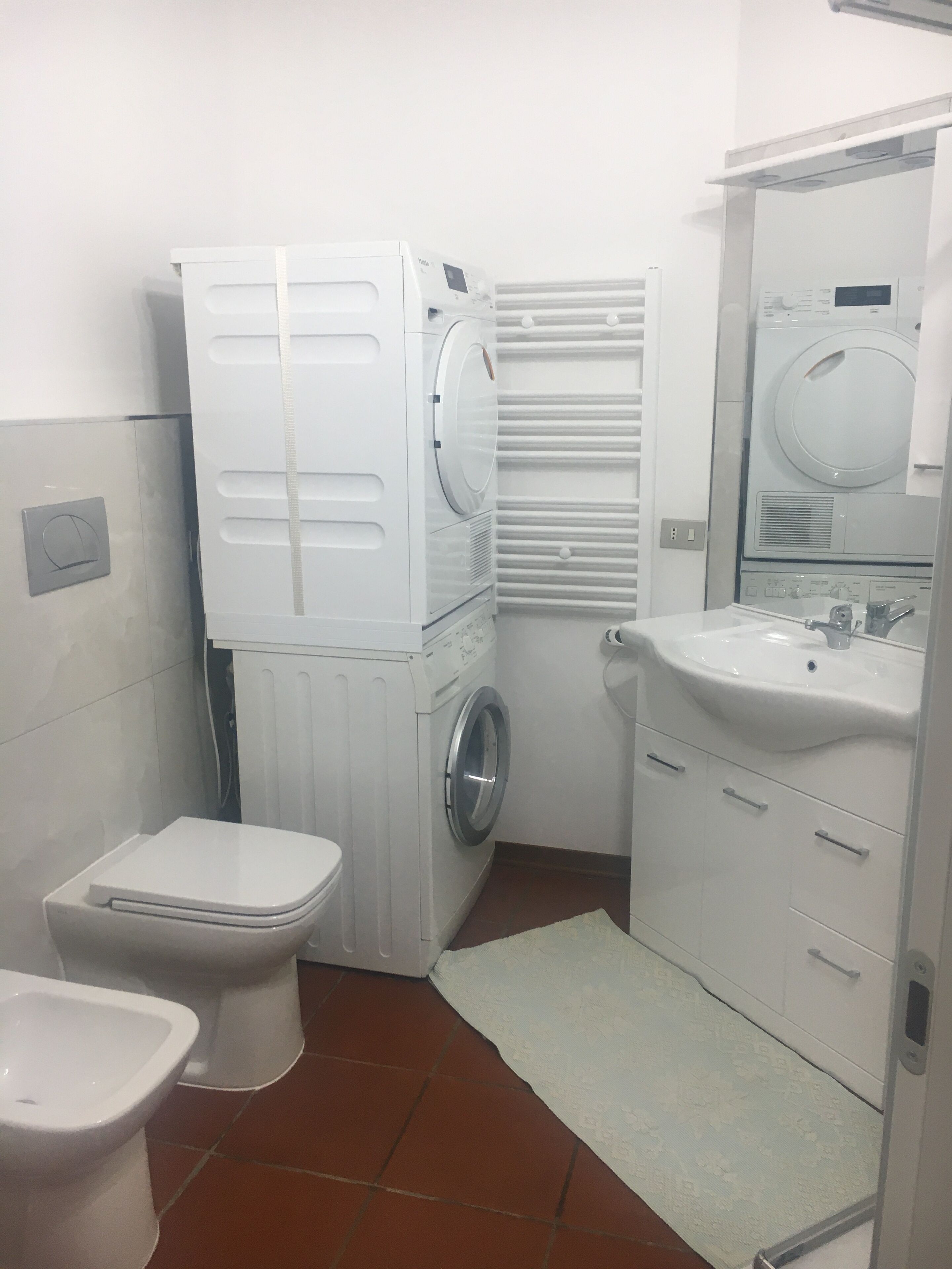 Un baño pequeño con inodoro, lavadora y lavamanos.