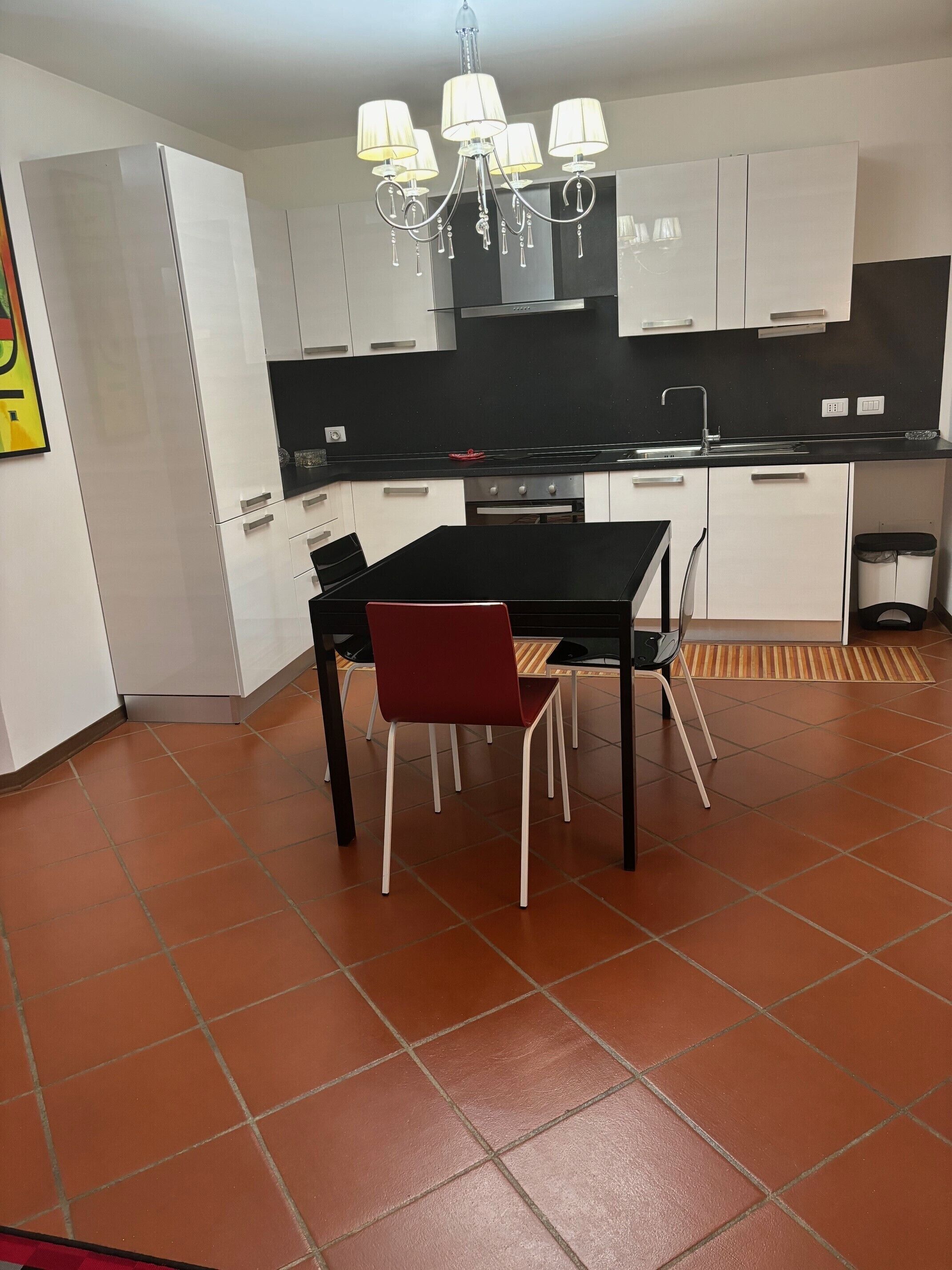 Une cuisine moderne avec des armoires blanches, un comptoir noir et une chaise rouge.