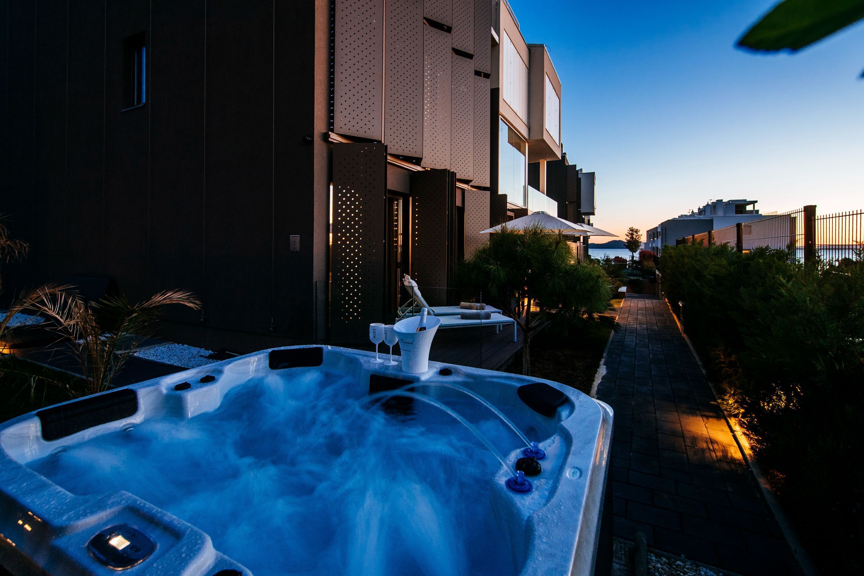Un jacuzzi en un patio con un edificio moderno al fondo.