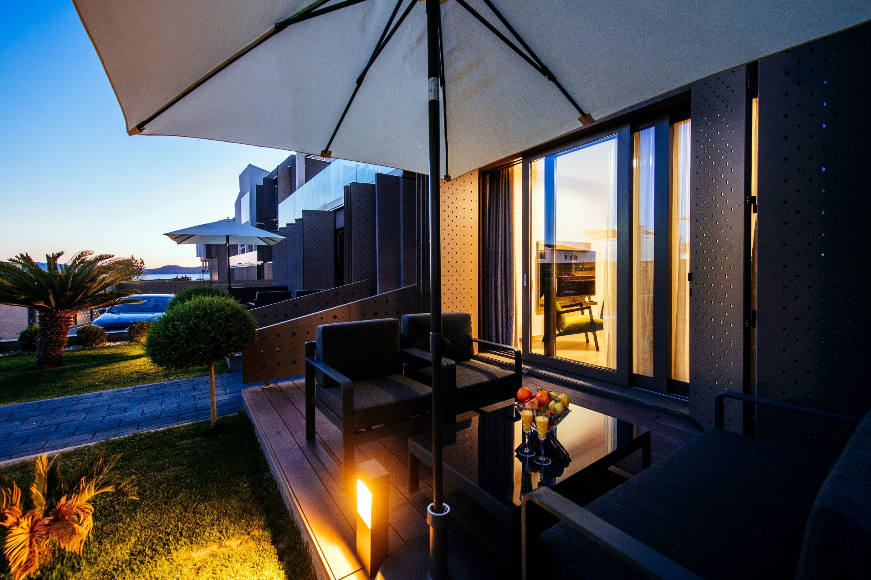 A modern outdoor seating area with a table, chairs, and a large umbrella.