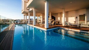 A rooftop swimming pool with lounge chairs and a covered seating area.