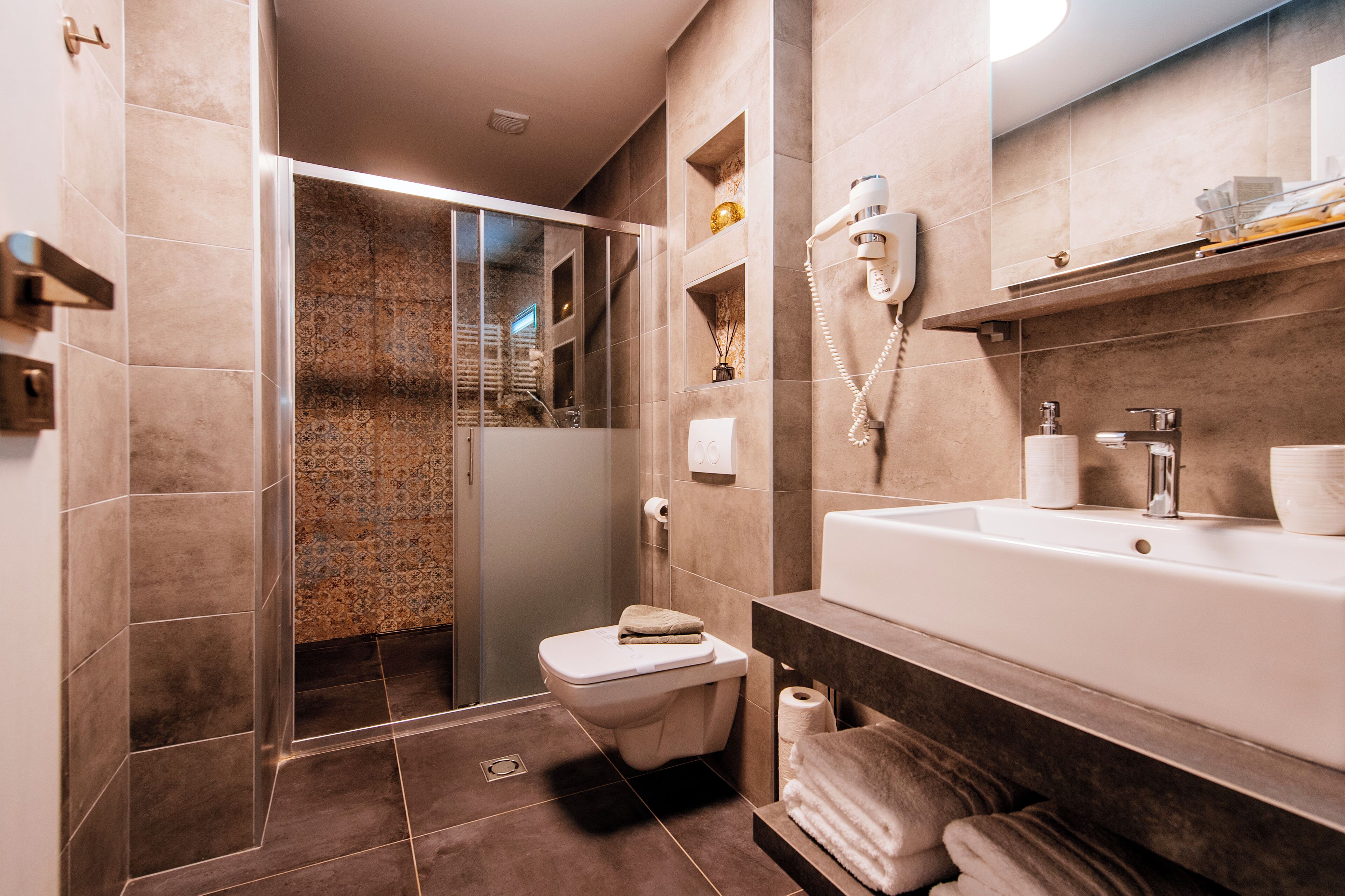 Ein modernes Badezimmer mit Duschkabine, Toilette, Waschbecken mit Spiegel und Handtuchhalter.