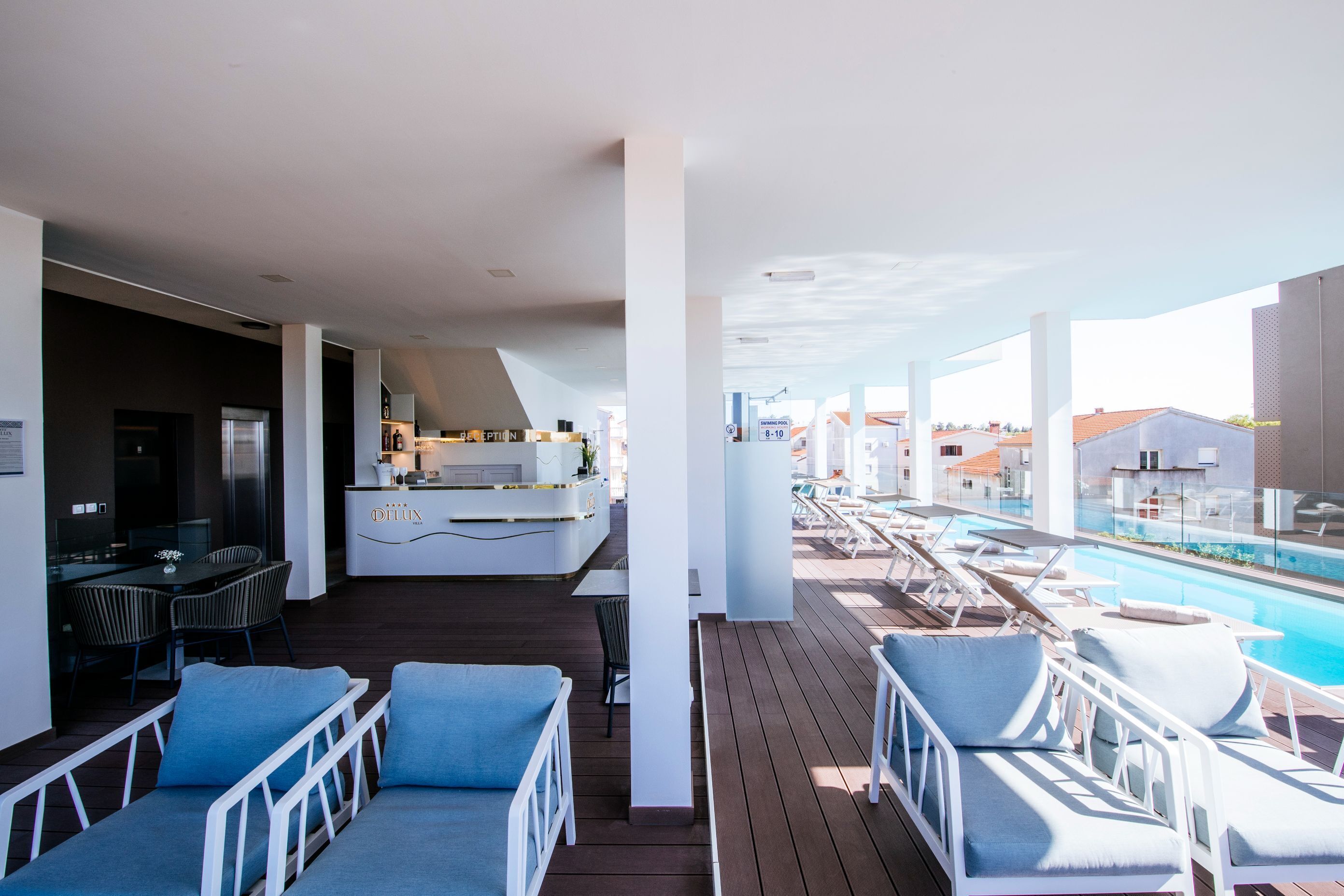 A modern outdoor deck with a pool, lounge chairs, and a bar area.